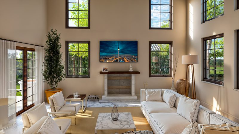 Double-height living room with two stories of arched windows and a stone fireplace.