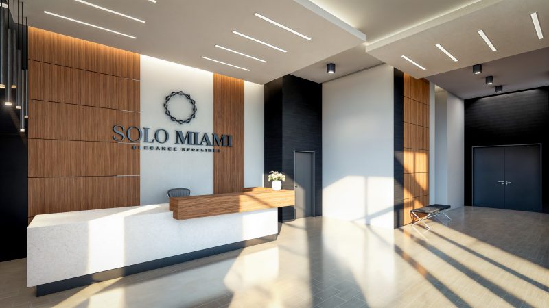 Reception desk against a walnut feature wall carrying the Solo Miami mark.